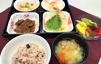 赤飯、野菜の味噌汁、肉を焼いた料理、天ぷら、小鉢２種類、フルーツ、デザート